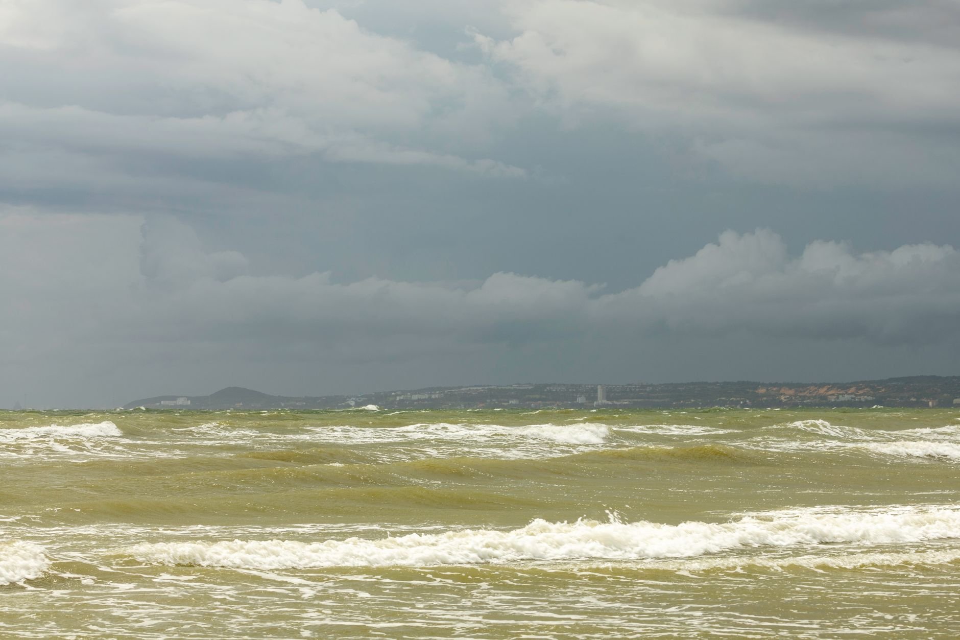 A captivating view of the ocean under a stormy sky. Turbulent waves and dark clouds create a dramatic seascape.