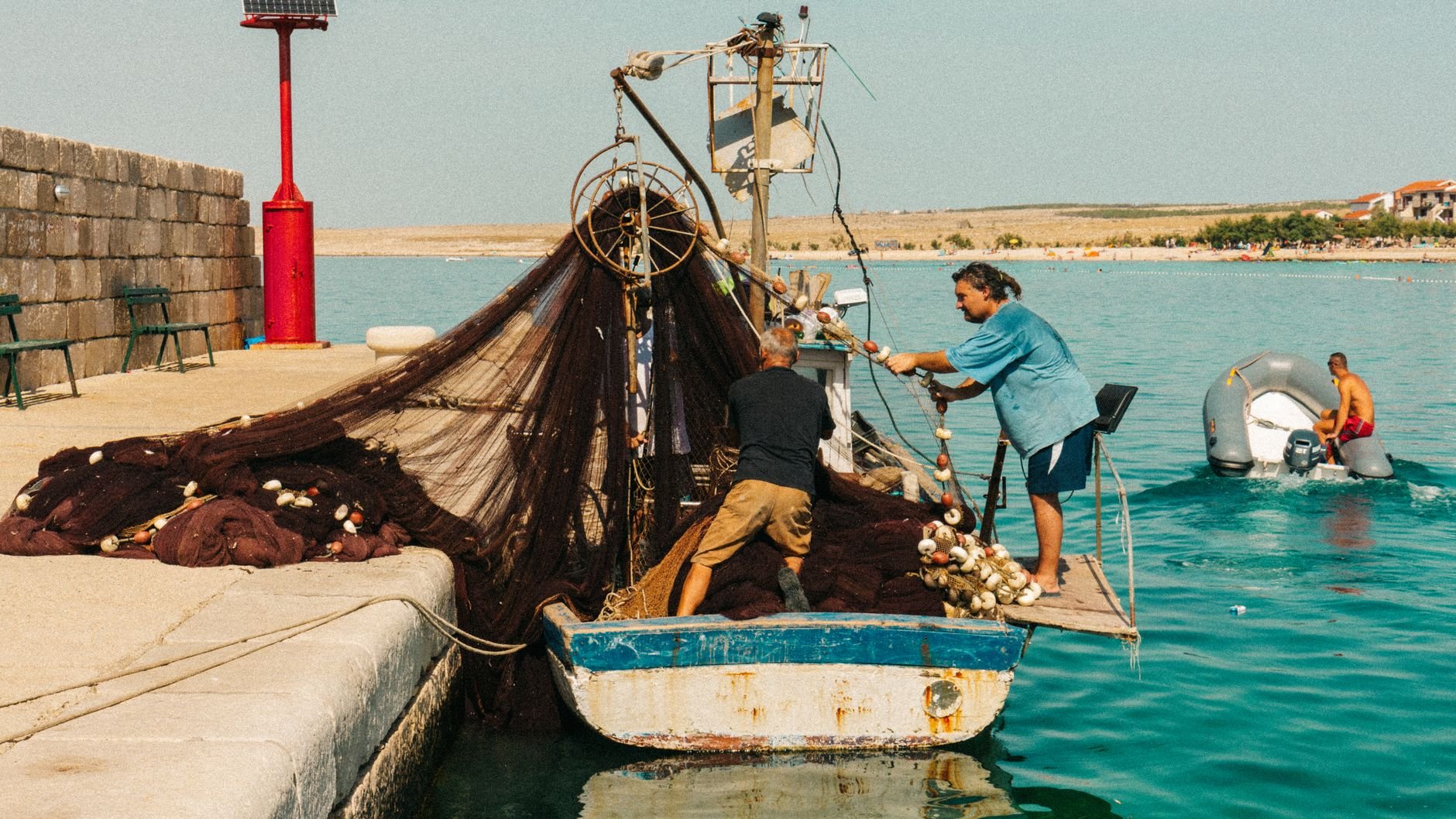 Fishermen pulling nets on a boat in the harbor of Zadar, Croatia, on a sunny day.